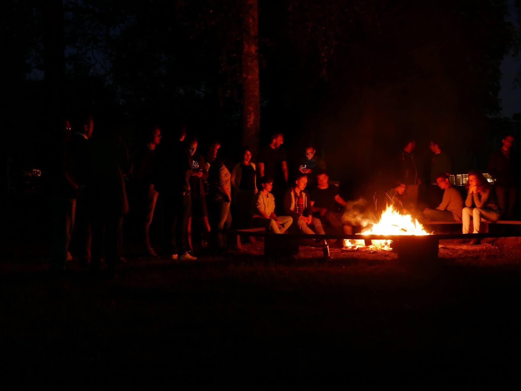 Group gathered around a bonfire at night in the woods