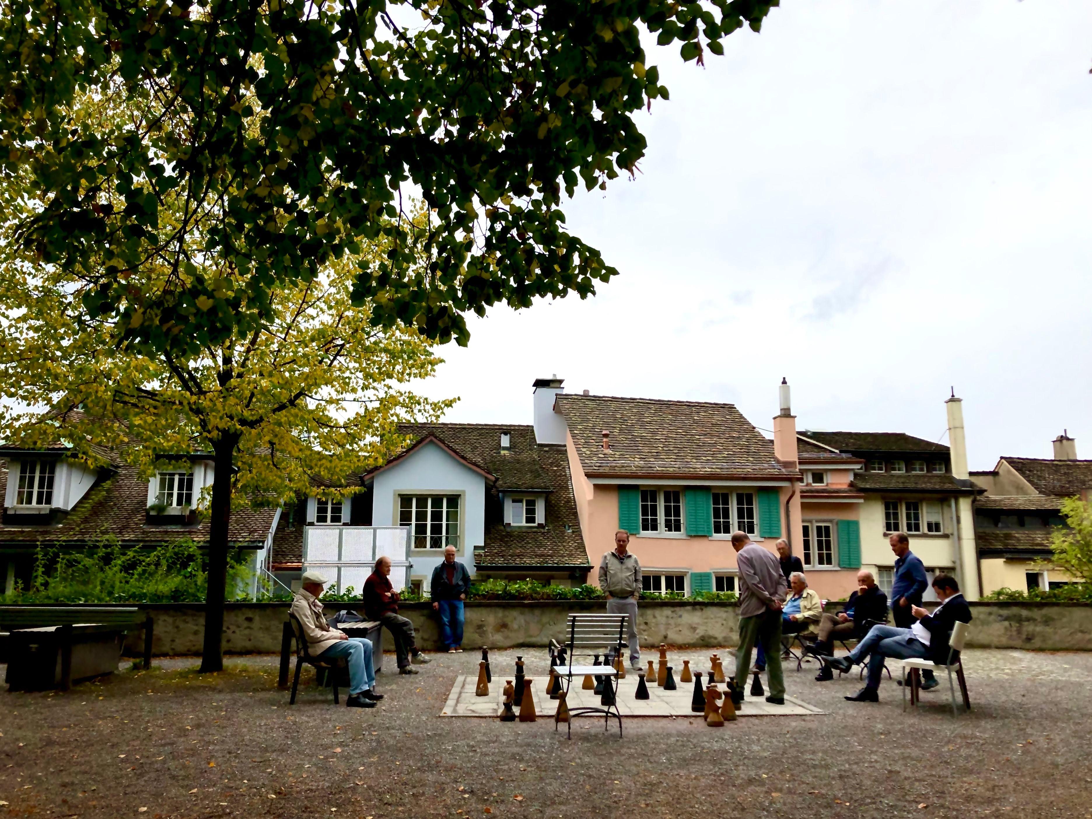 People playing giant outdoor chess in a Swiss town square