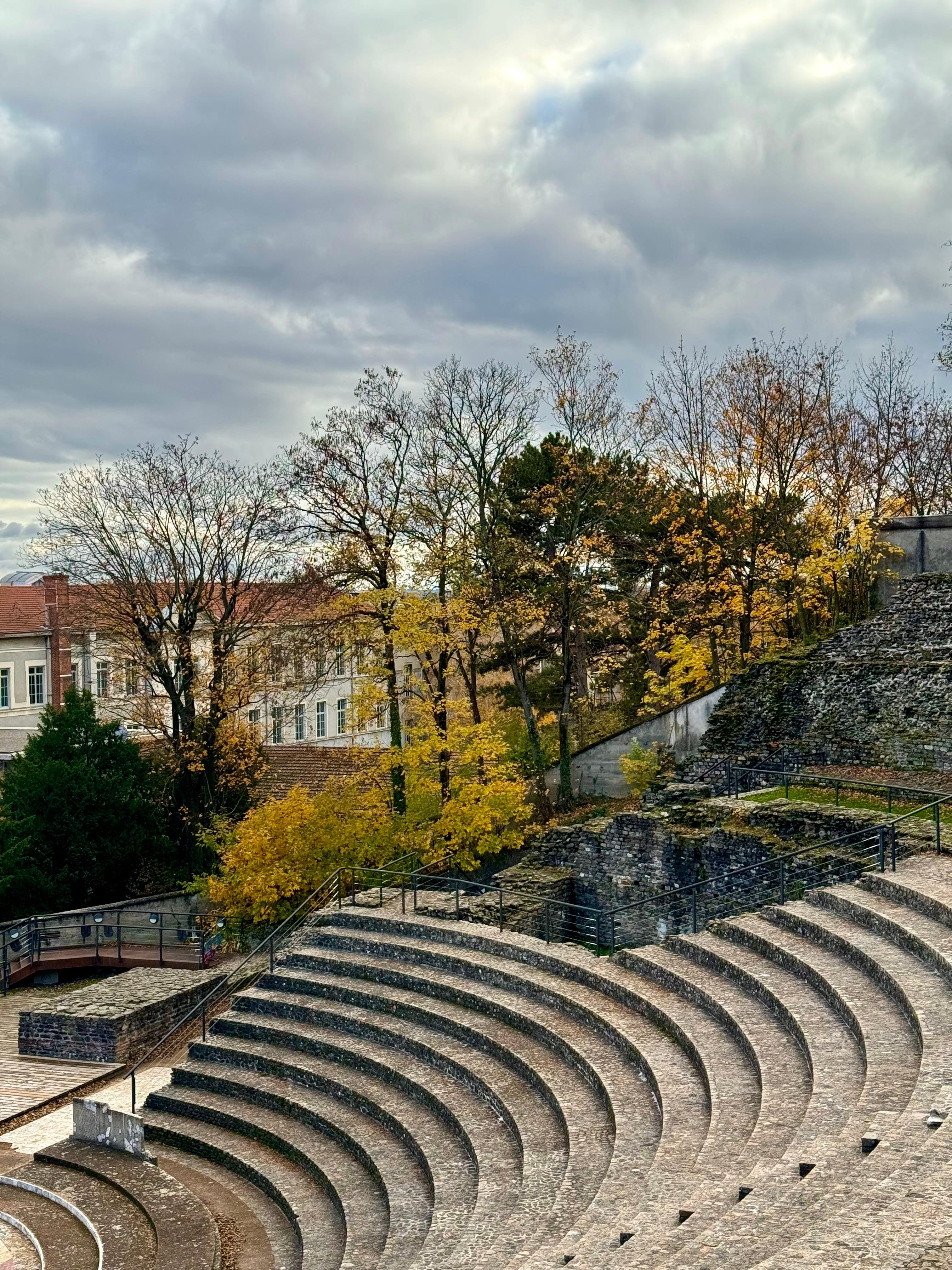 Ancient Roman amphitheater ruins surrounded by autumn foliage in Lyon