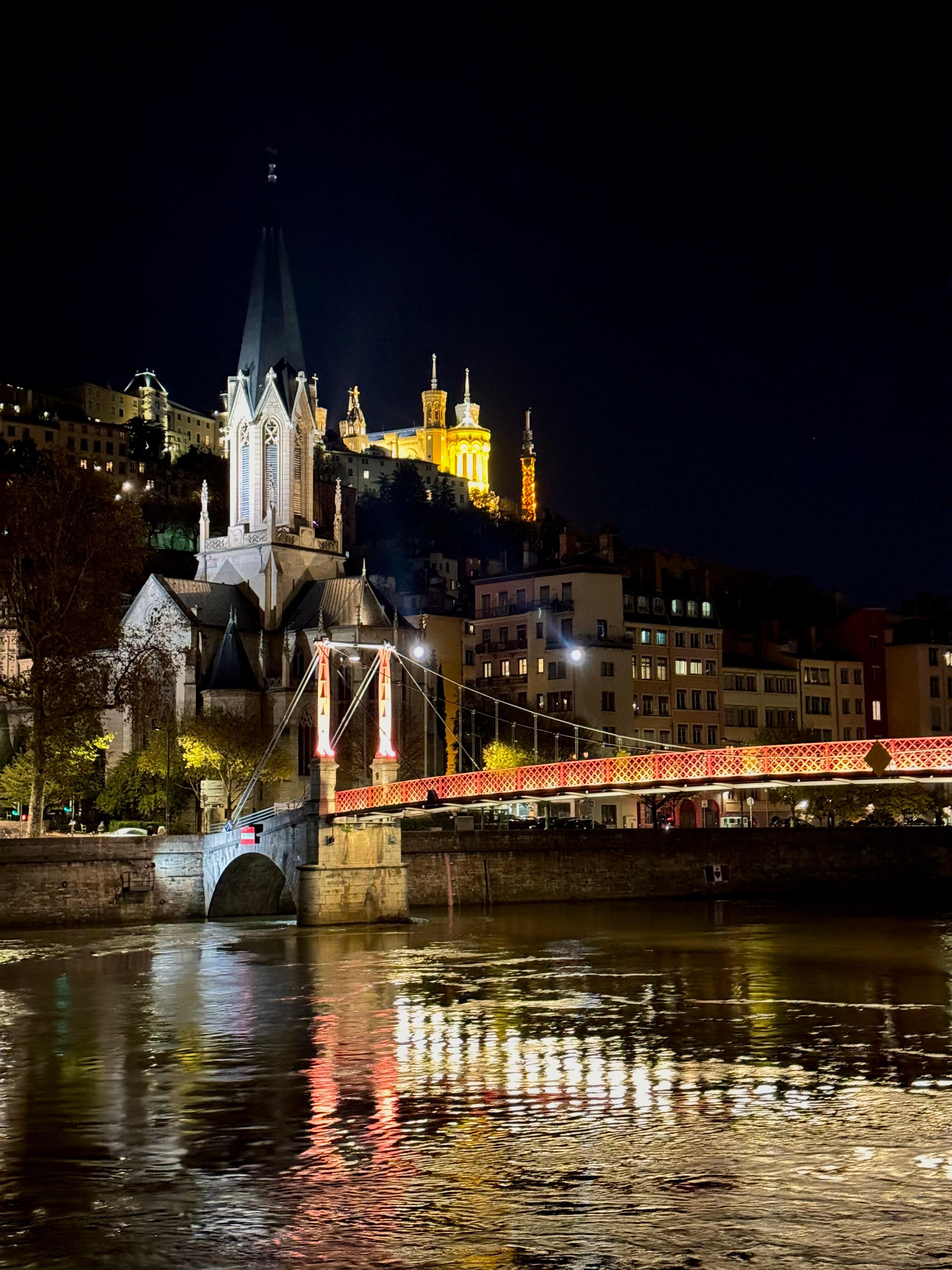 Lyon at night with illuminated Fourviere basilica and red footbridge