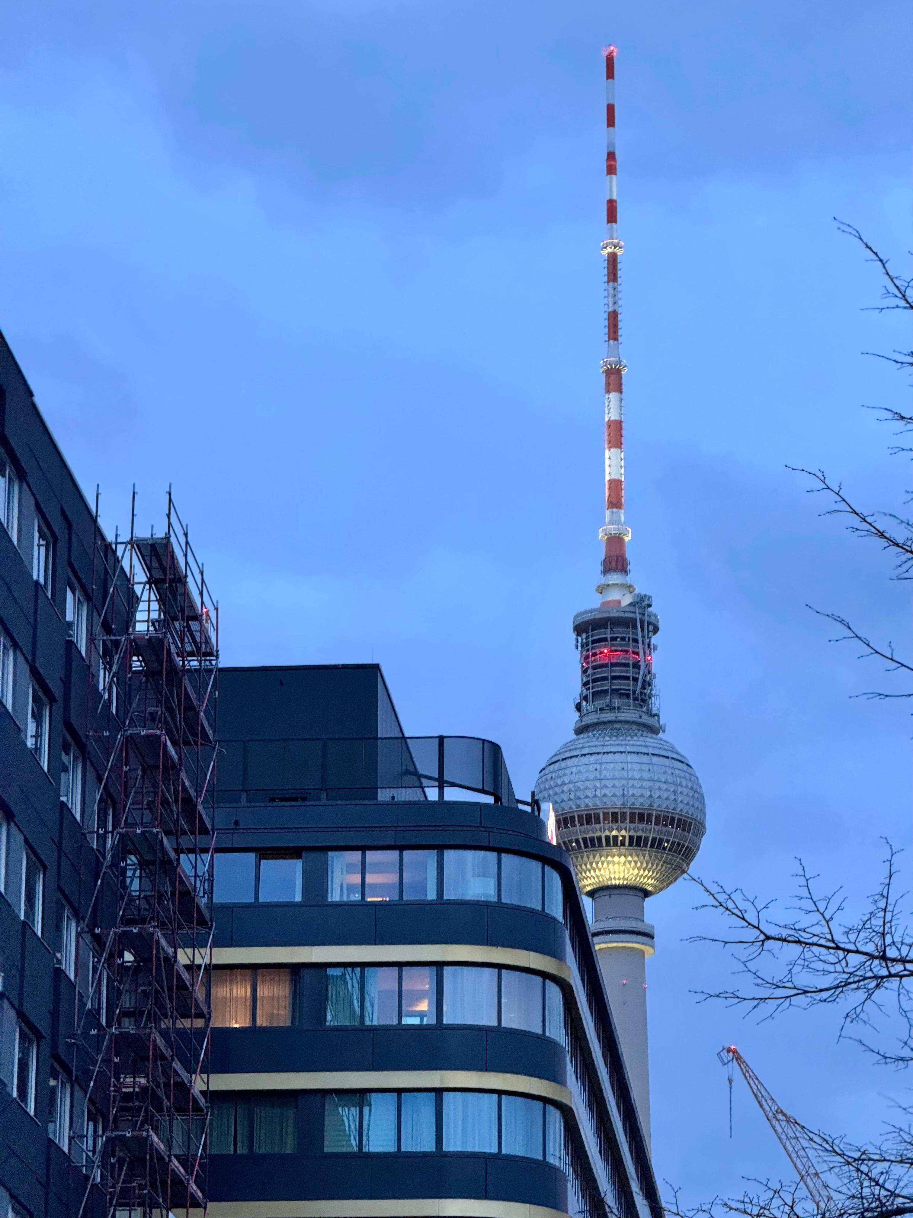 Berlin TV Tower rising behind apartment building at dusk
