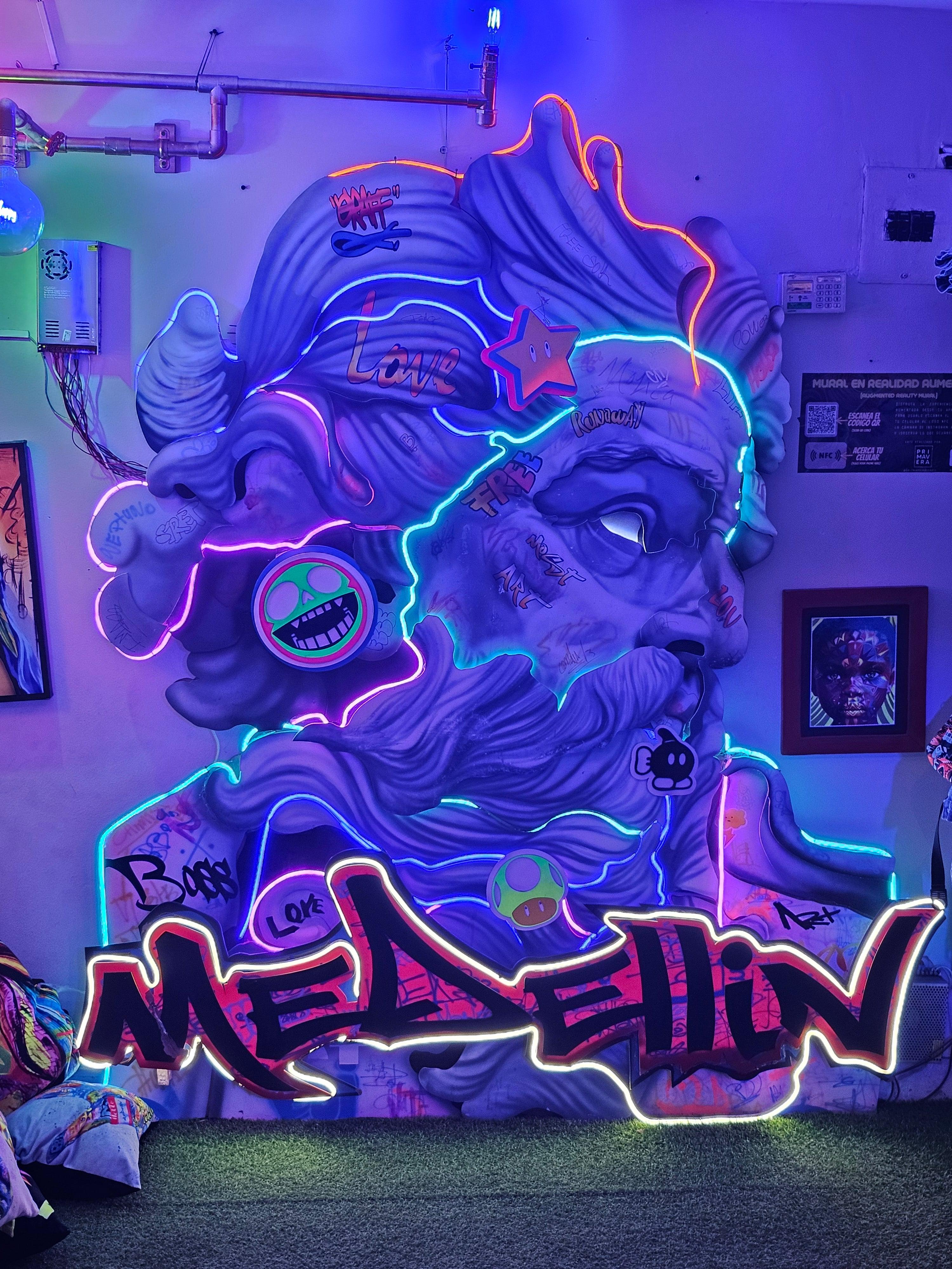 Neon-lit face sculpture with graffiti lettering in Medellin