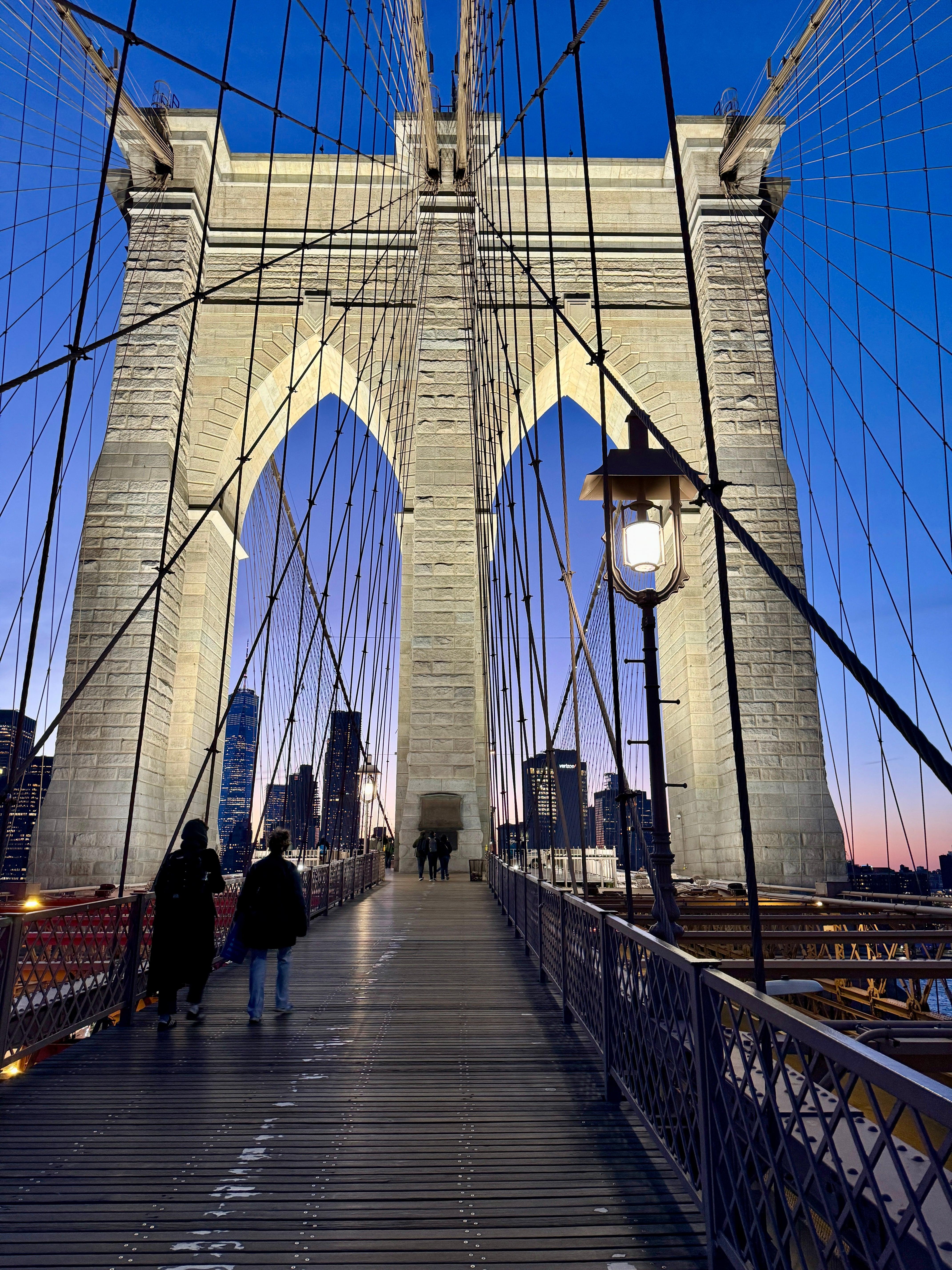 Walking across Brooklyn Bridge pedestrian path at twilight