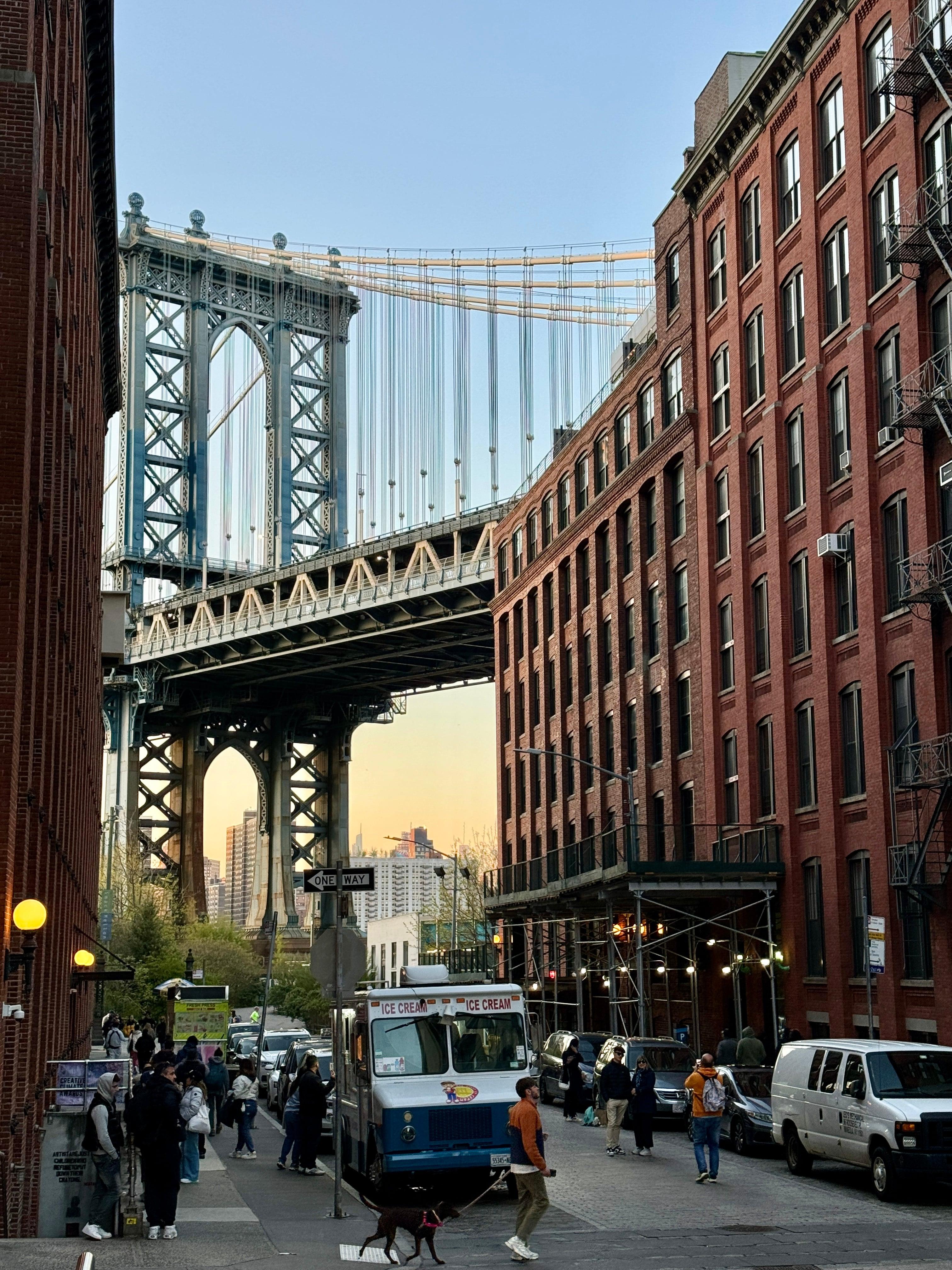 Manhattan Bridge framed between brick buildings in DUMBO at sunset
