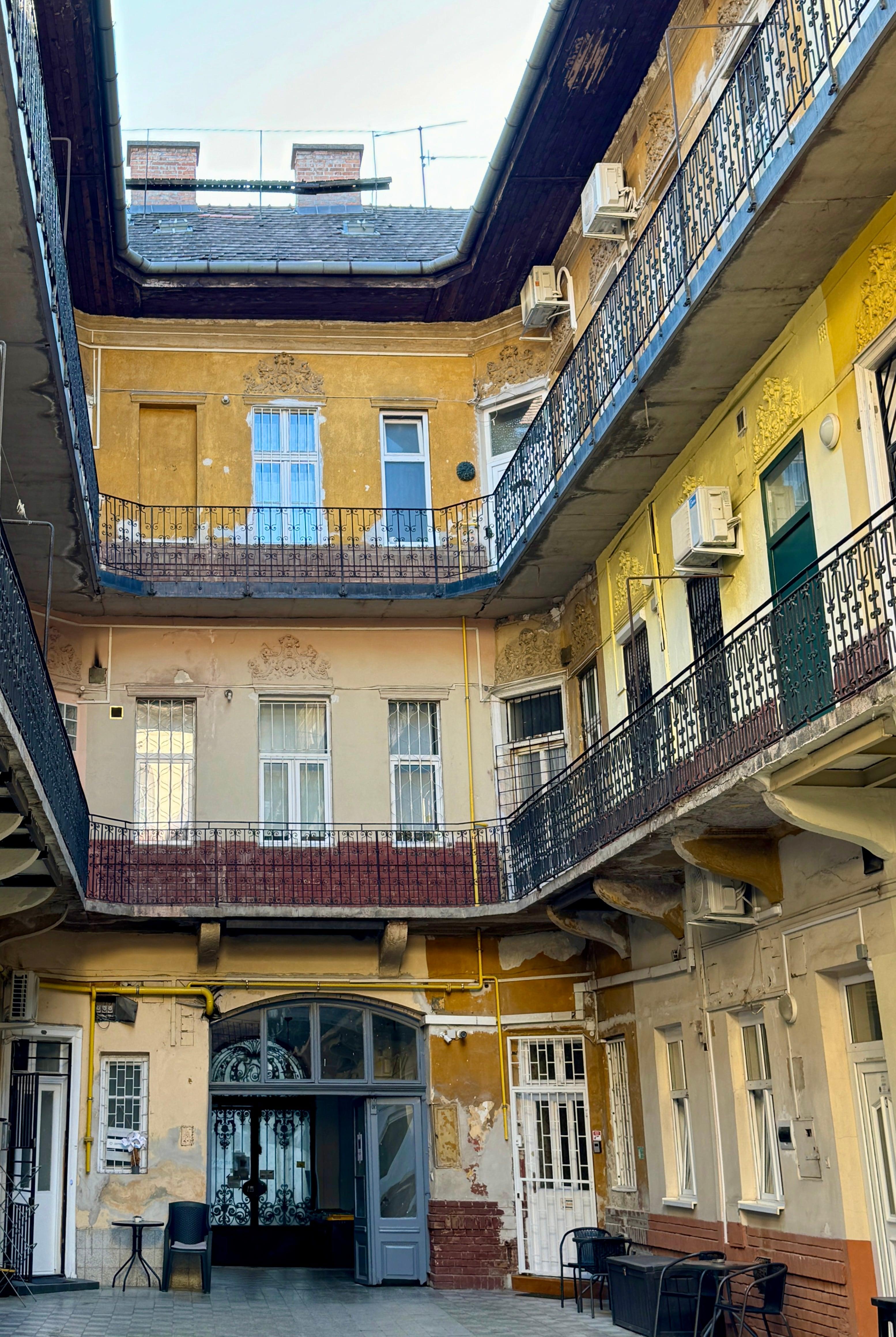 Weathered inner courtyard with ornate iron balconies in Budapest