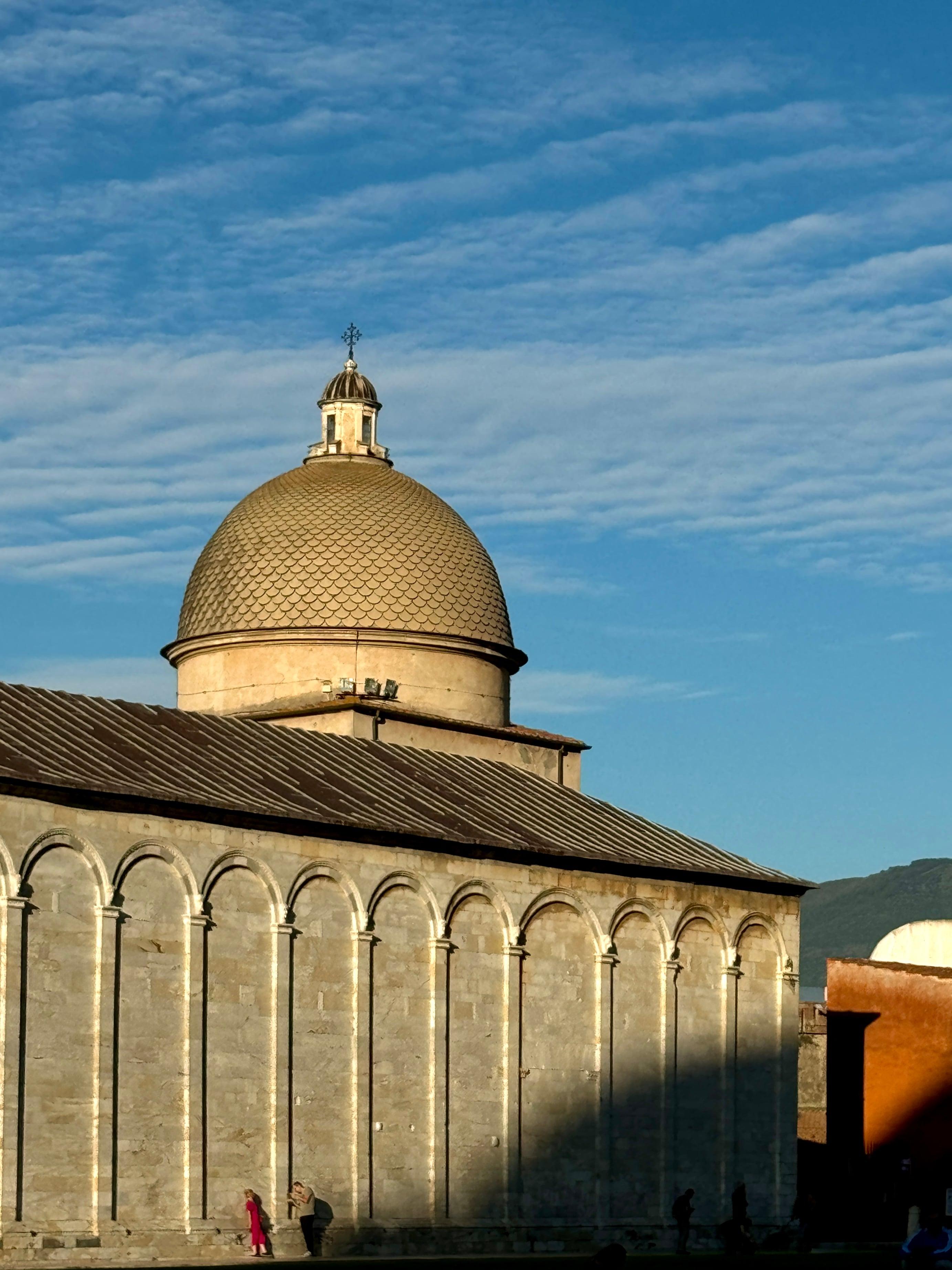 Domed baptistery with arched stone walls in Pisa at golden hour