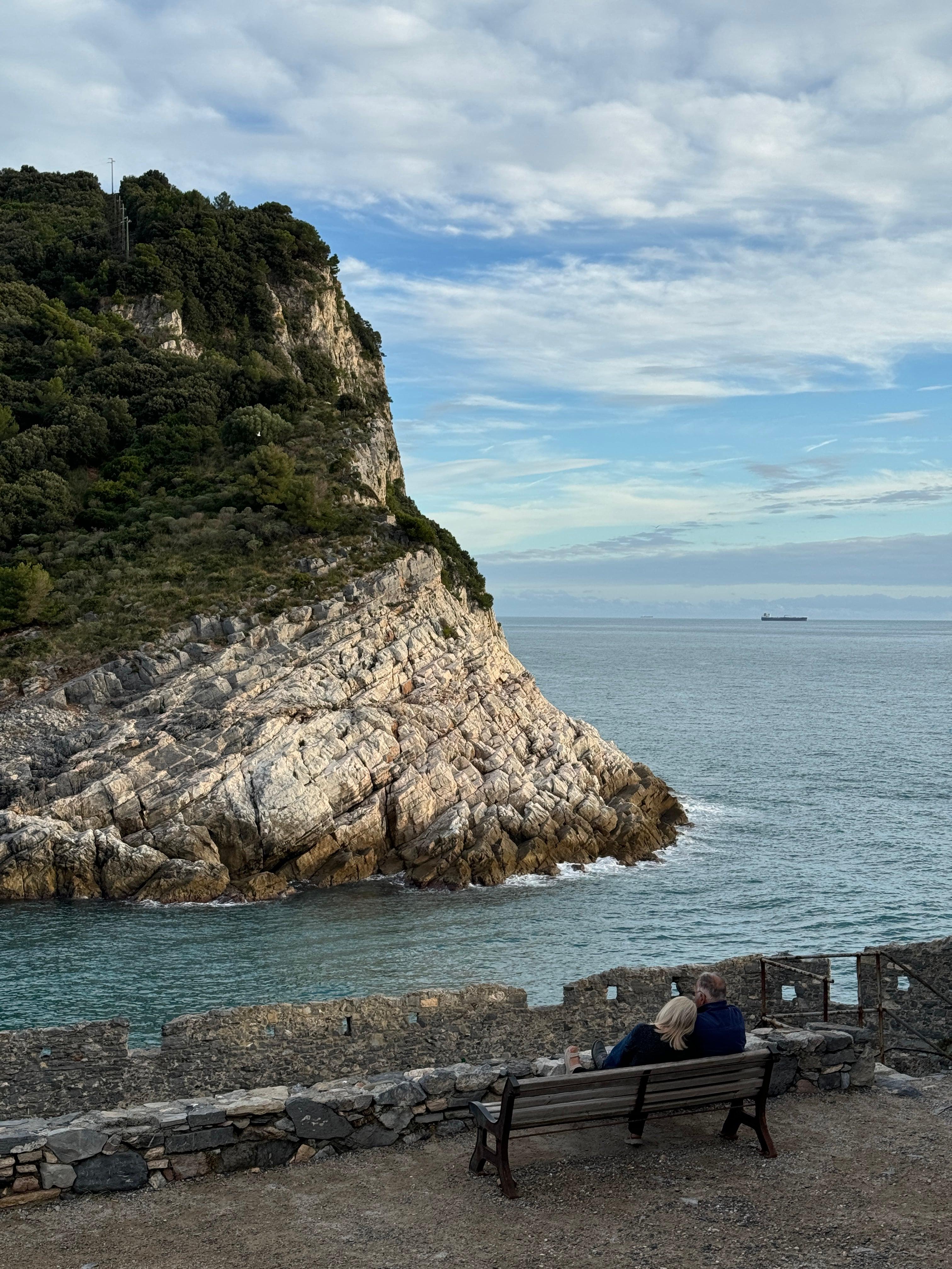 Couple on a bench overlooking rocky cliffs and the Ligurian Sea