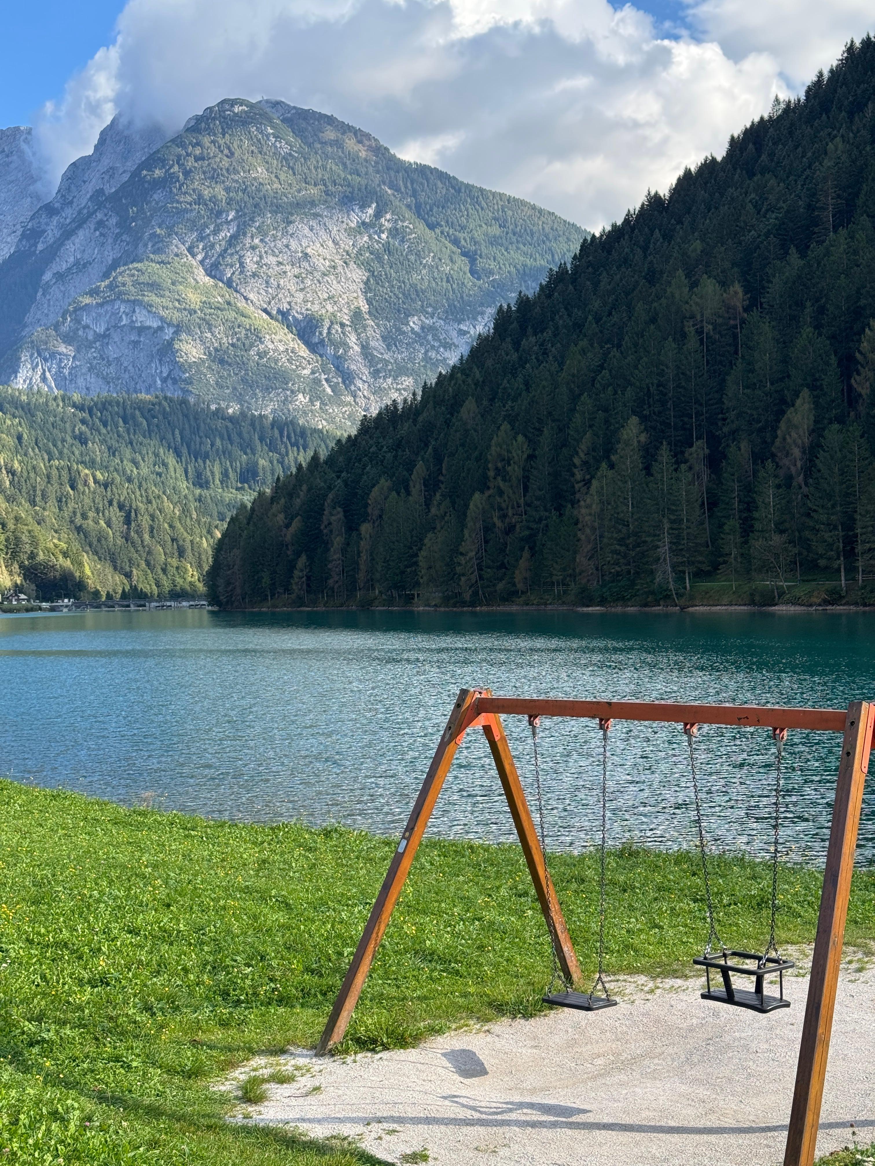 Wooden swing set by a turquoise alpine lake with Dolomite peaks